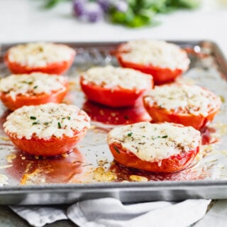 A sheet pan with Tomatos on top with white cheese melted on them