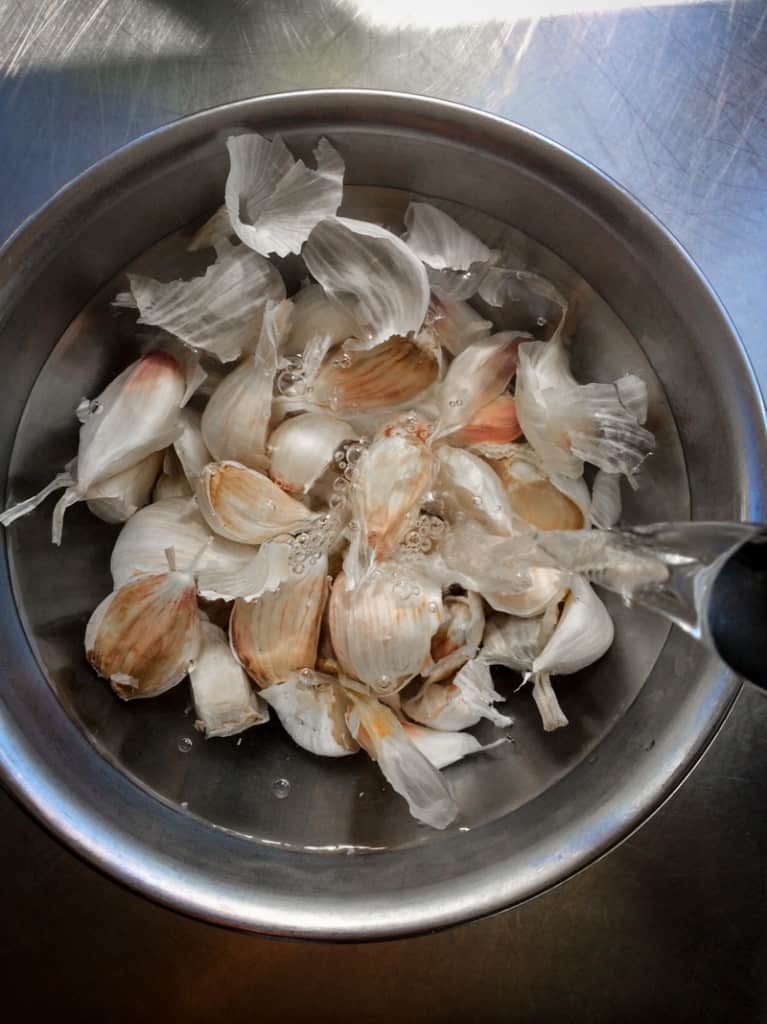 pouring boiling water over garlic cloves