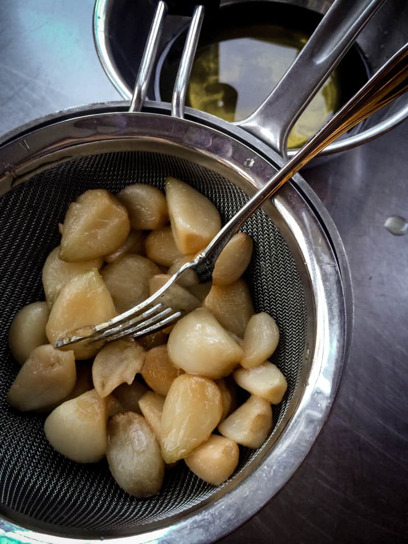 garlic cloves in a mesh sieve