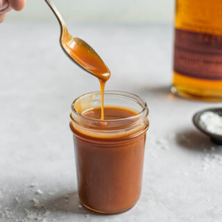 dipping a spoon into a jar of caramel sauce
