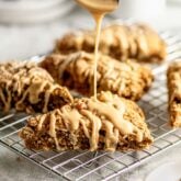 the scones on a cooling rack being drizzled with icing