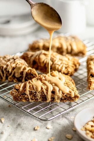 the scones on a cooling rack being drizzled with icing