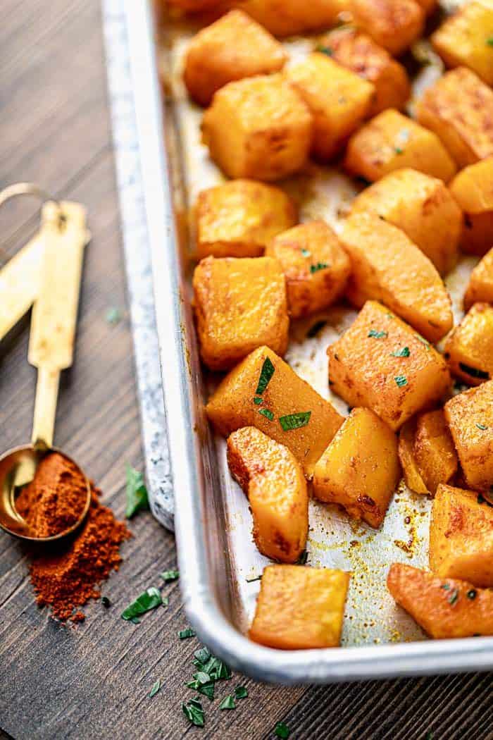 a close up of roasted butternut squash with smoked paprika on a sheet pan