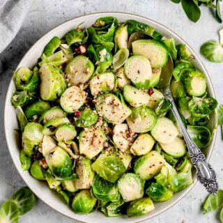 brussels sprouts with hazelnuts and sage in a white bowl with a spoon