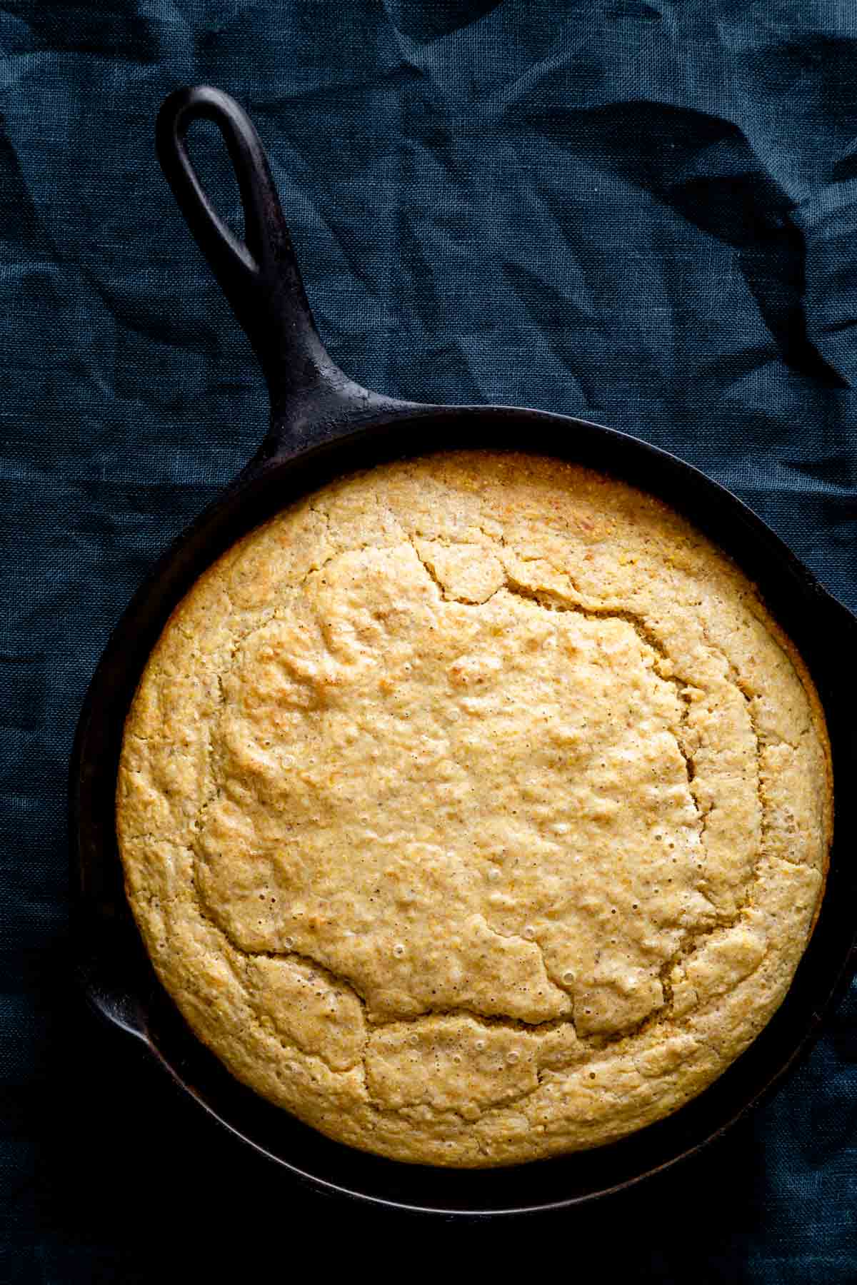 the skillet of cornbread from overhead on a navy napkin