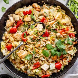 Chicken Cabbage Stirfry in a black iron pan with a large serving spoon