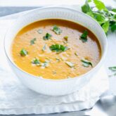 curry soup in a white bowl with cilantro on top