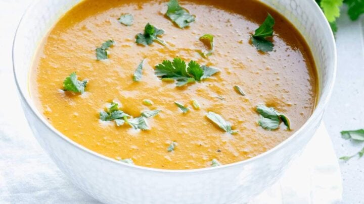 curry soup in a white bowl with cilantro on top