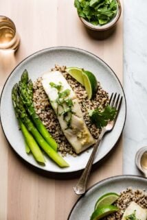 a plate of fish with asparagus and lime
