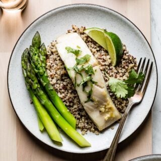 cod on quinoa with a fork and lime wedges from overhead