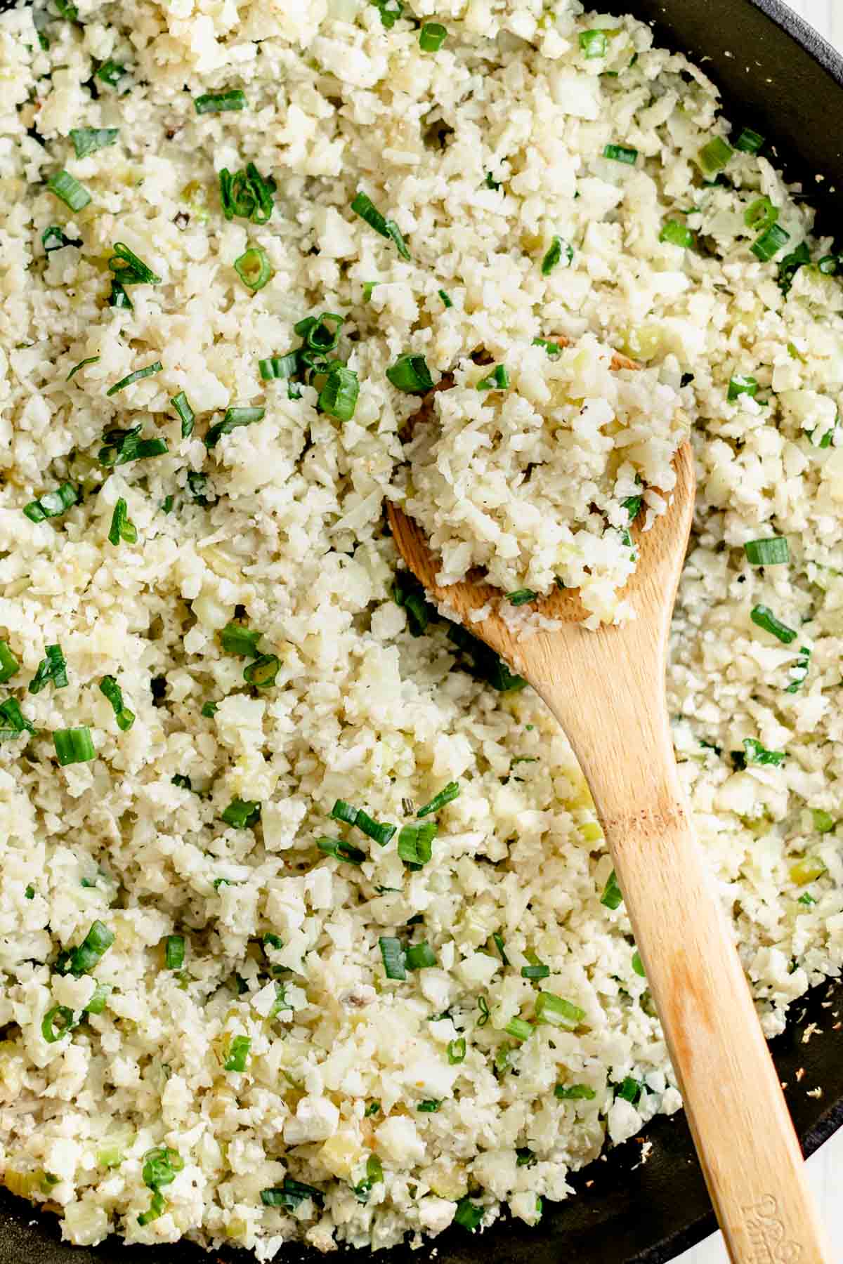 very close up of the riced cauliflower in the skillet with the scallion greens stirred in