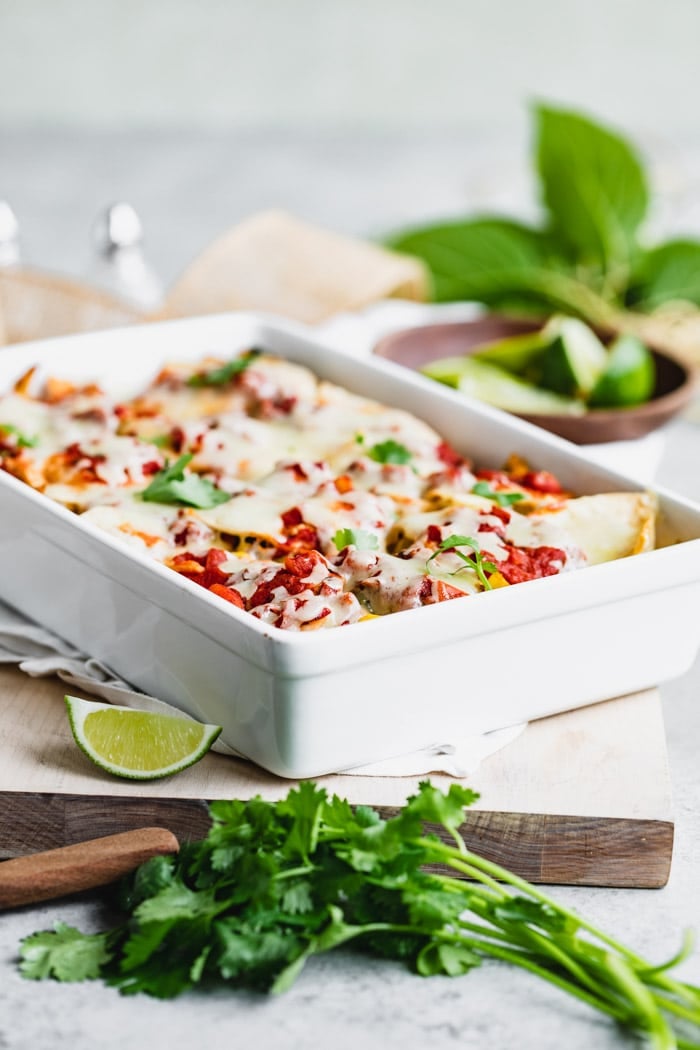 A side view of a casserole dish filled with tortillas, cheese, and chilaquiles filling.