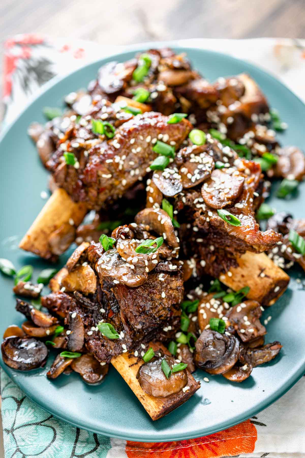 oval teal platter with braised short ribs and mushrooms on it