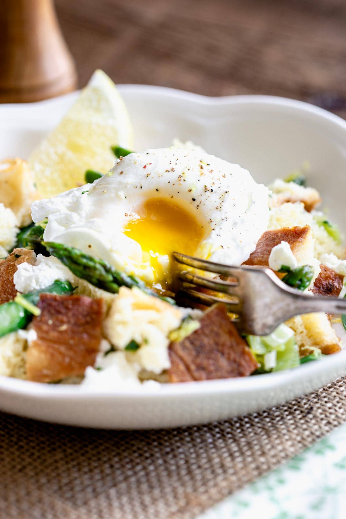 side view of runny poached egg over the salad
