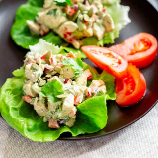a close-up of the lettuce cups with tomato wedges on a black plate