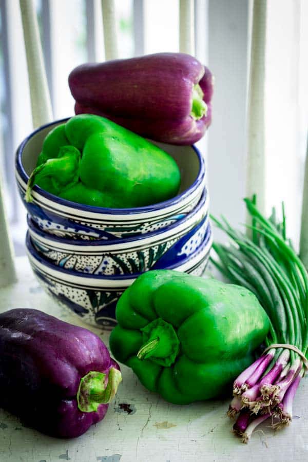green and purple peppers with stack of bowls