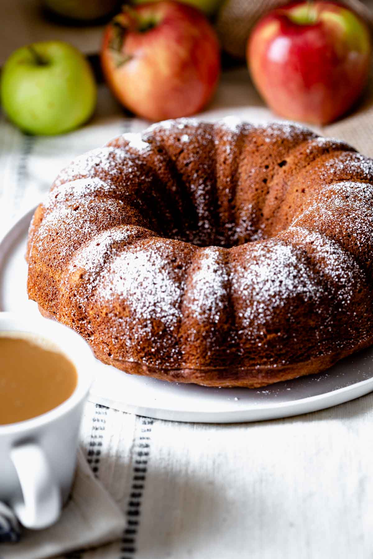 snack cake with a cup of coffee in foreground and apples in background