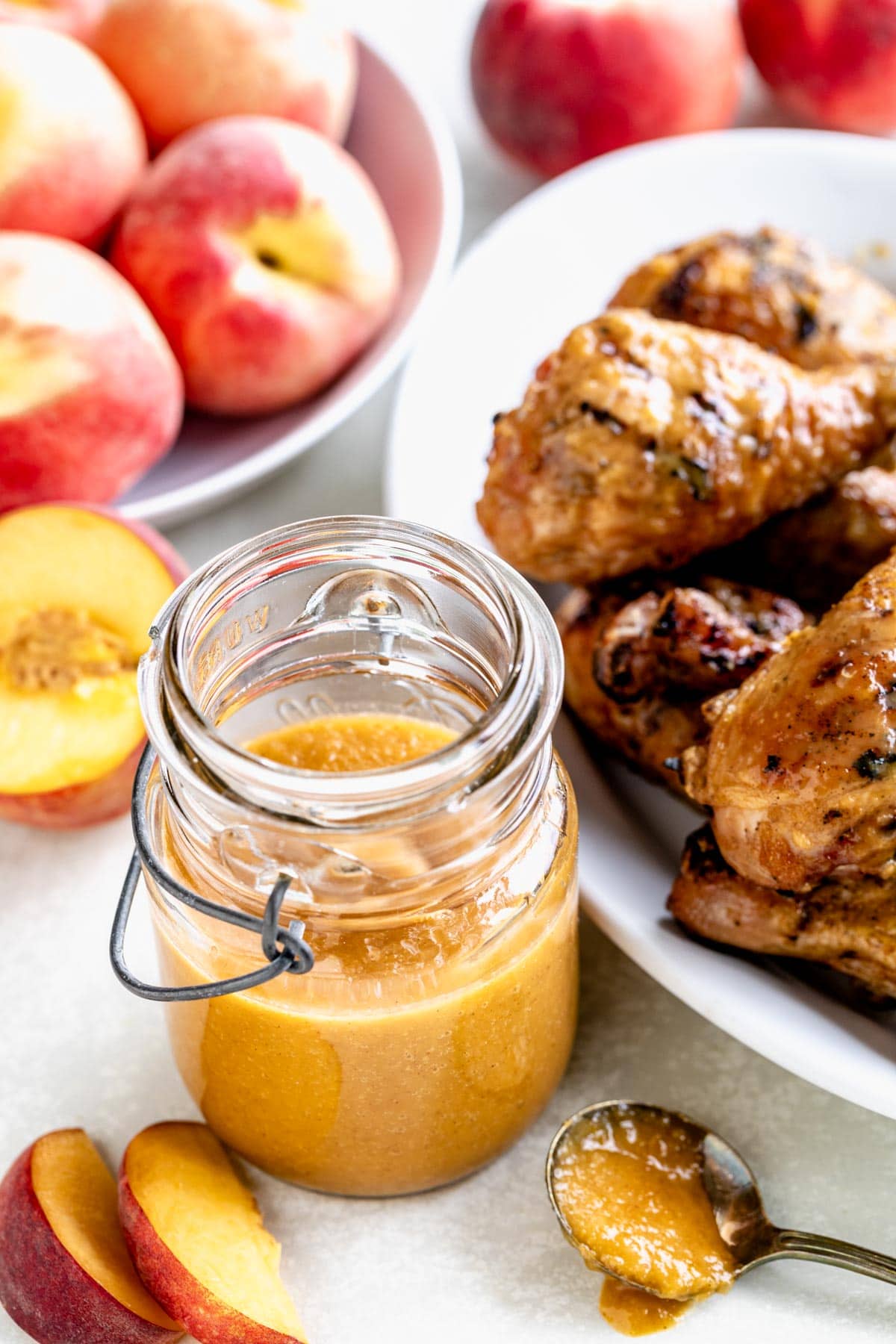 peach barbecue sauce in a jar beside fresh peaches