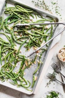 a pan of roasted green beans from overhead with a set of tongs on top