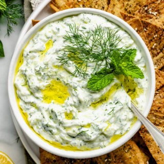 a closeup of the tzatziki with mint and dill garnish