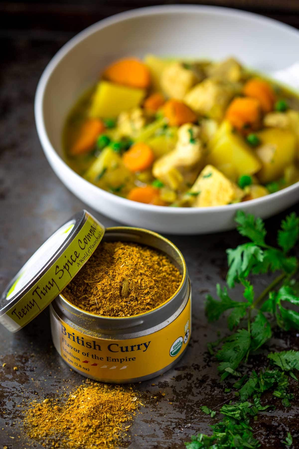 a tin of curry powder with the curry stew in the background