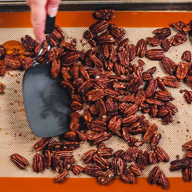 Nuts on a silpat with a person stirring