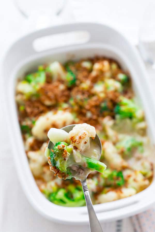 a white casserole dish with broccoli and cauliflower casserole with browned breadcrumbs on top