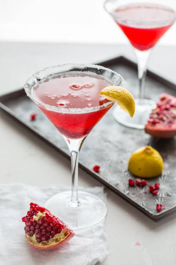 Two Pomegranate Lemon Drop Martinis in a martini glass garnished with a lemon wedge.