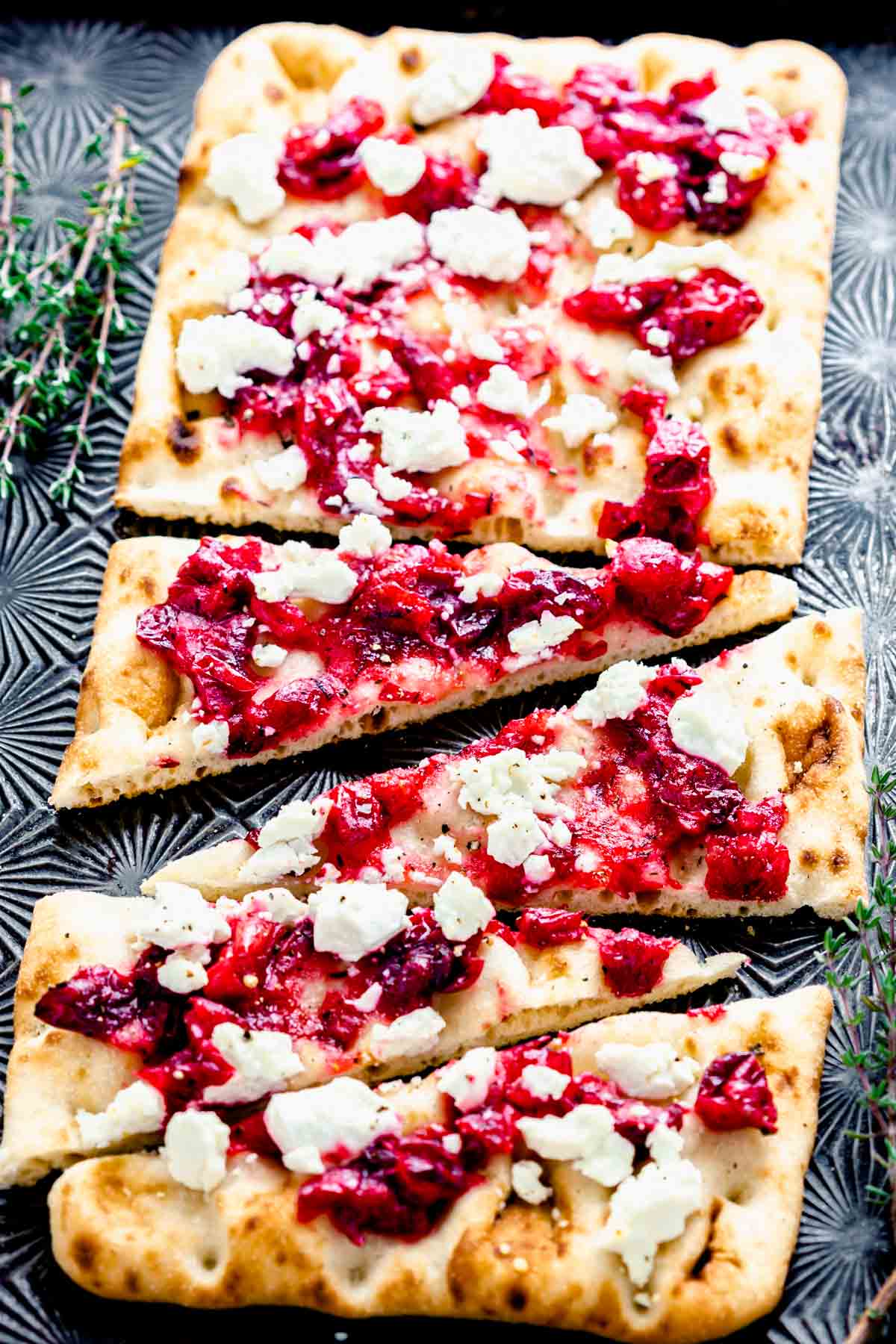 cut cranberry flatbread on a Black baking sheet