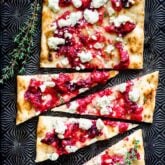 cut cranberry flatbread on a Black baking sheet
