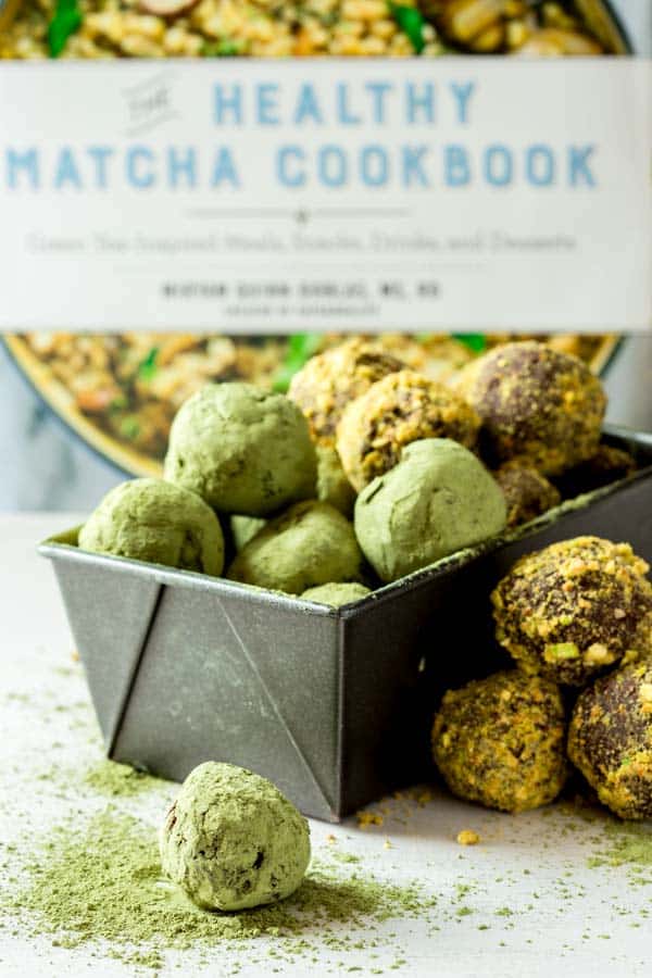 Matcha Chocolate Truffles in a bread pan with a cookbook behind them.