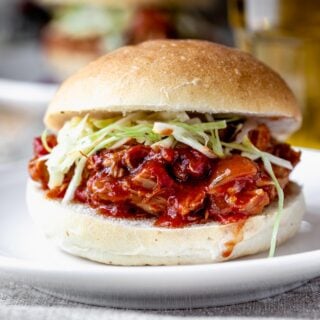 a bun with pulled chicken with sauce spilling out