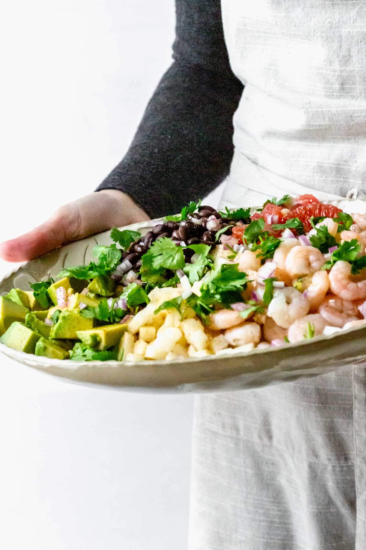 a person holding a platter of the salad
