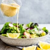 pouring lemon dressing over a salad