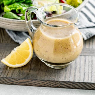 a glass pitcher of dressing with a wedge of lemon