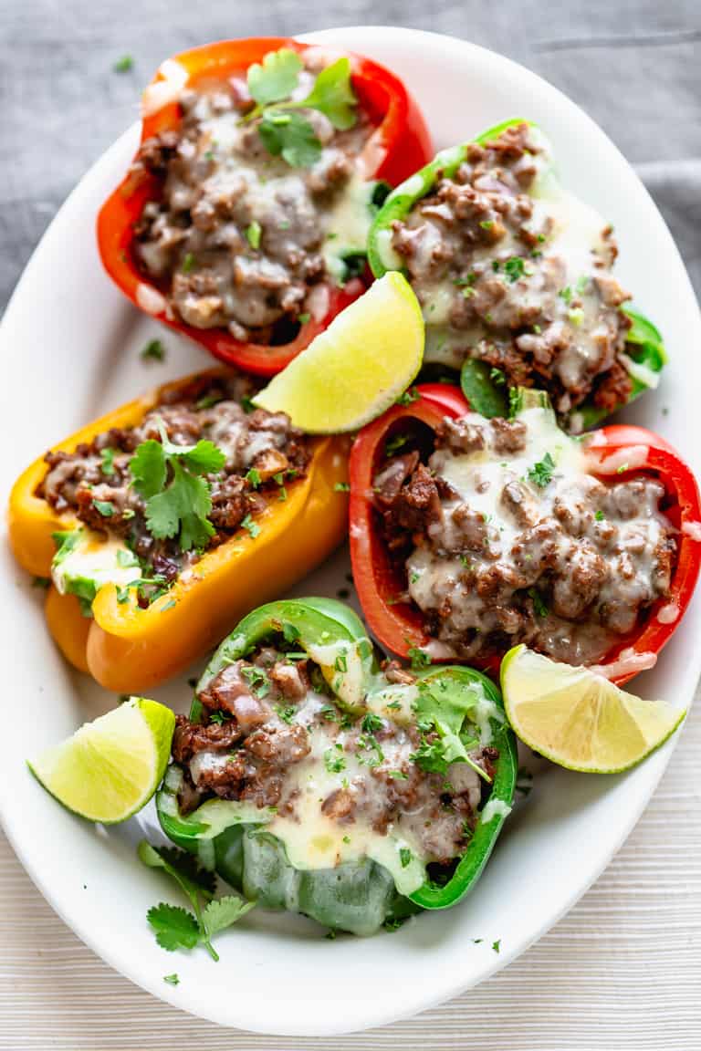a platter filled with colorful bell peppers stuffed with low carb mexican beef and topped with cheese