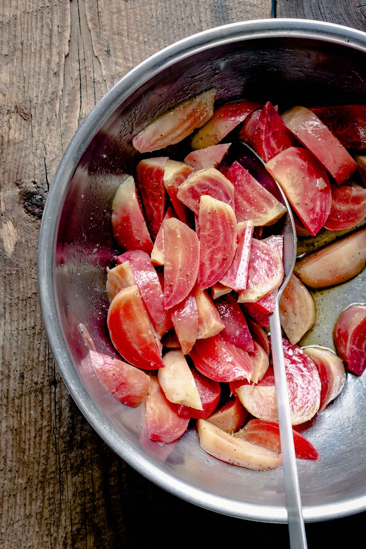 Chioggia beets in a stainless bowl with vinegar, oil and salt and pepper.