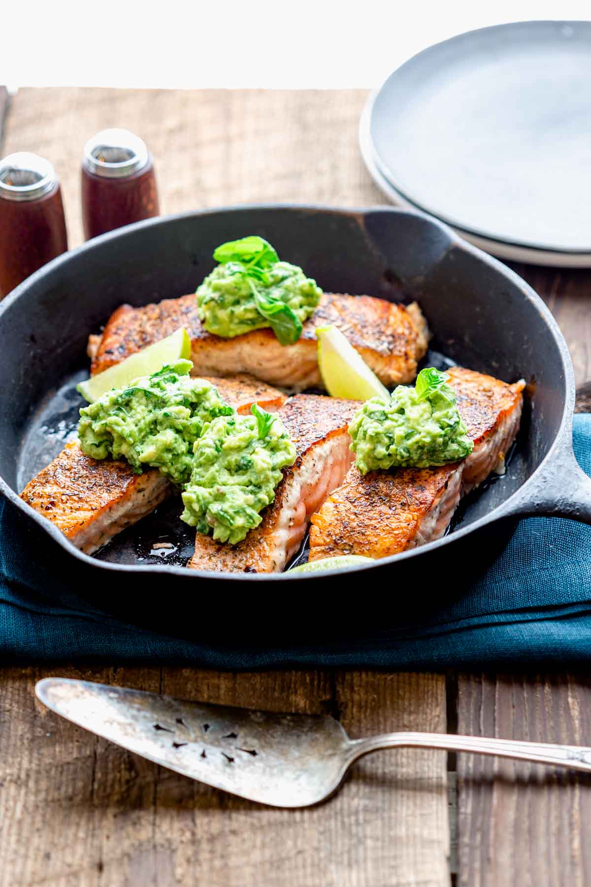 the skillet of salmon on a wooden table top with a metal serving spatula