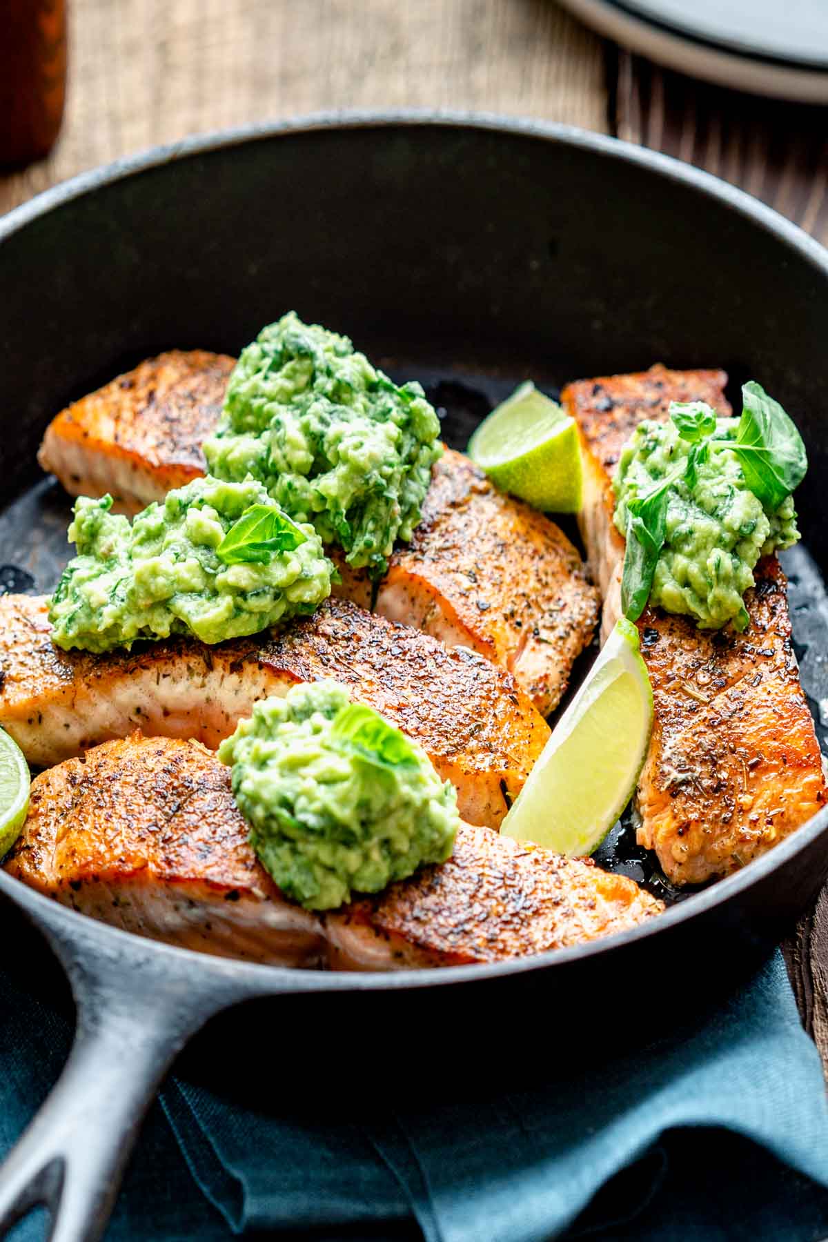 close up of the salmon in the skillet with the avocado on top