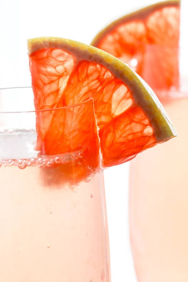 Close up of Sparkling Grapefruit Champagne Cocktail with a wedge of grapefruit on the rim of the glass