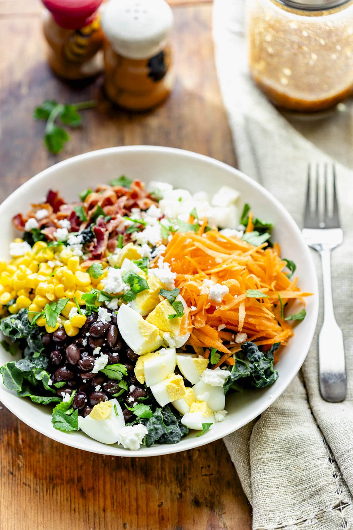 the cobb salad with the dressing behind it in a jar