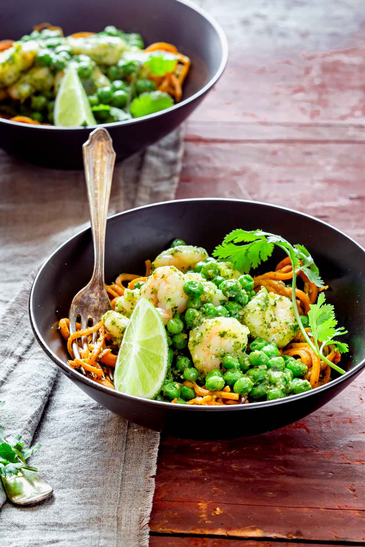 the sweet potato noodle dinner in a black bowl on a red wooden table