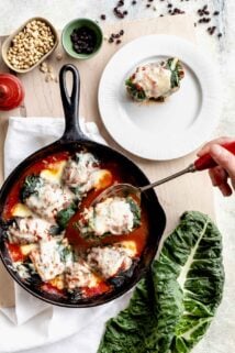 swiss chard rolls in a skillet, one is on a plate and another is being lifted up on a slotted spoon