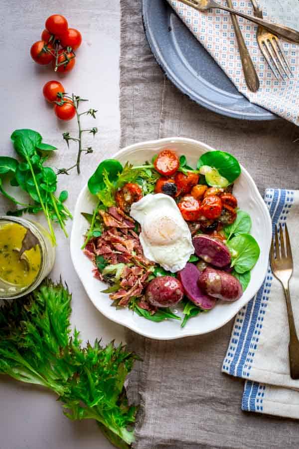 Brunch Salad with Poached Eggs on a plate alongside lettuce and dressing
