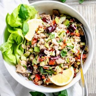 Mediterranean tuna salad in a white bowl with lemon wedges