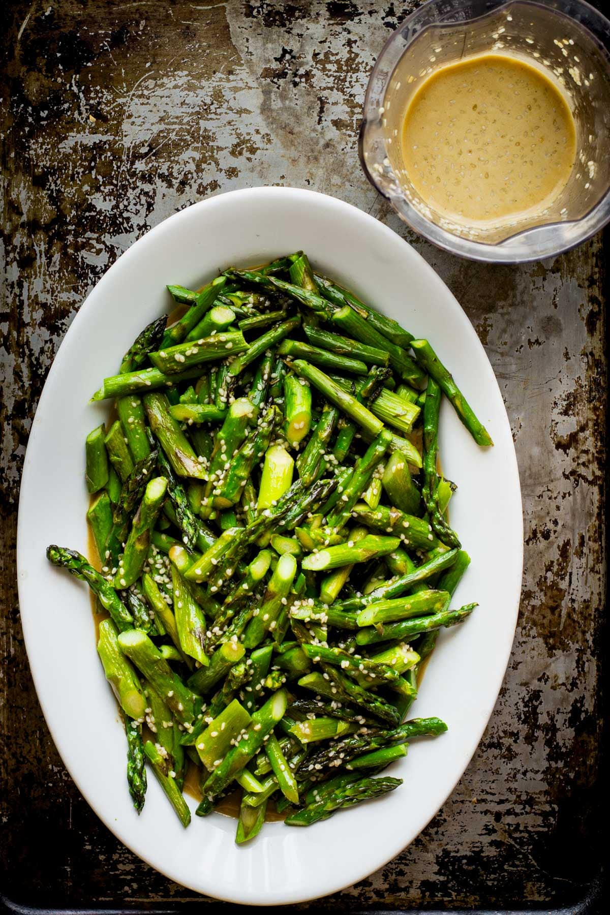 the oval platter of the asparagus with dressing next to it
