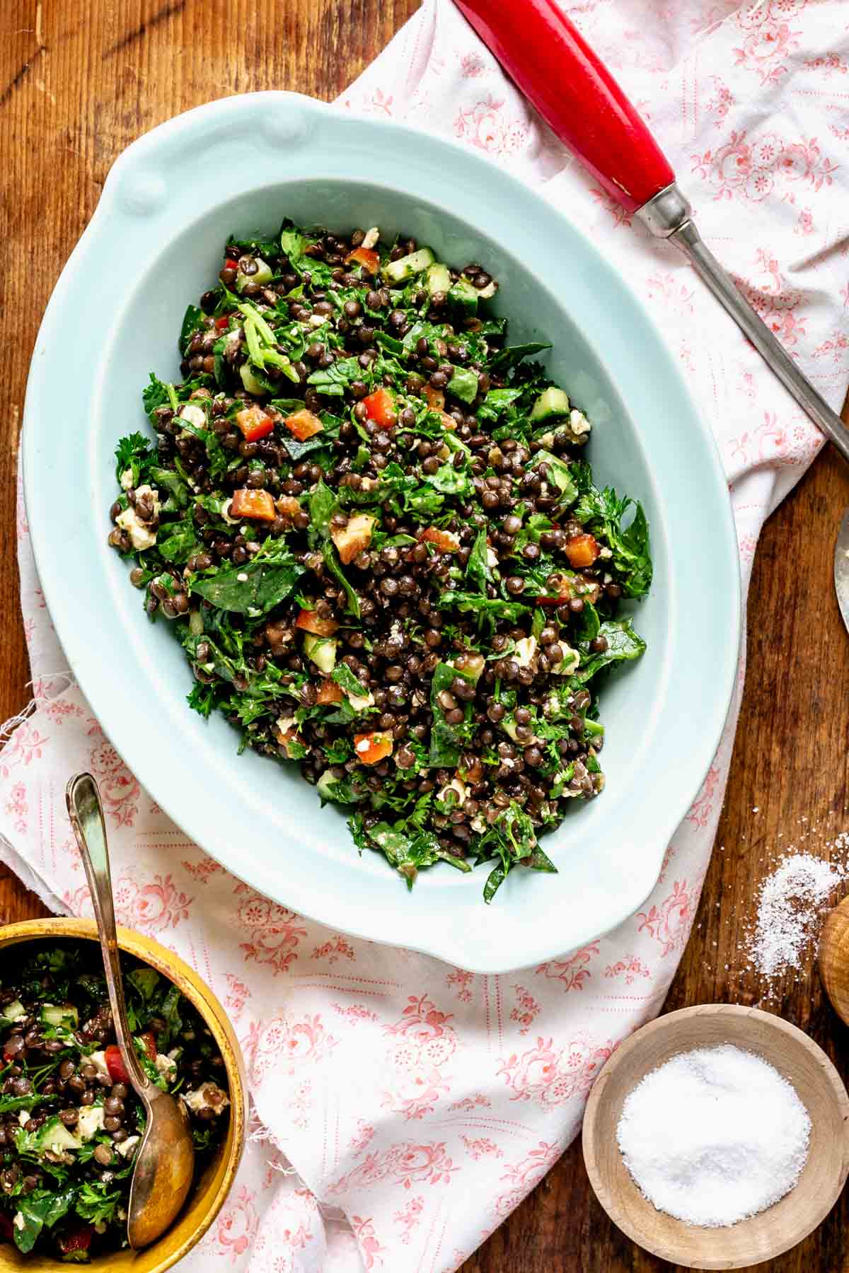 overhead of black lentils on a board with salt and a dish of lentils in a serving bowl