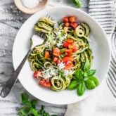 Zucchini Noodles with tomatoes on top in a white bowl.