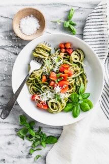 Zucchini Noodles with tomatoes on top in a white bowl.