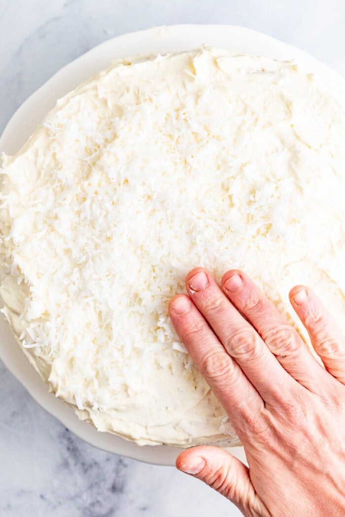 pack the coconut onto the frosting all over the sides and the top of the cake